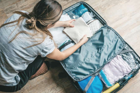 A girl is packing clothes or unpacking things from a suitcase. Preparing for a travel during the holidays or returning from a trip.の写真素材