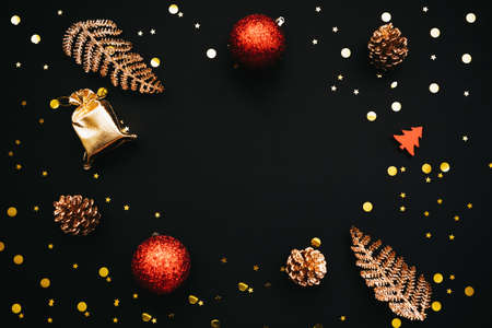 Many different festive gold baubles are scattered on a dark background. There is space in the middle for text or copy space. Christmas or New Year conceptual background.の写真素材