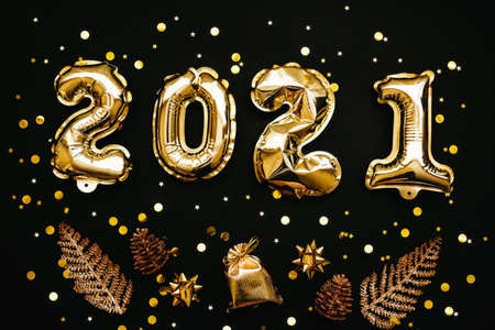 Gold numbers 2021 and next to them holiday items on a black or dark background. Christmas or New Year background.の写真素材
