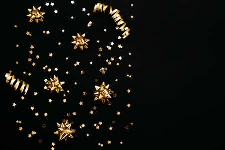 Various gold items on a black or dark background. Festive conceptual Christmas or New Year background or Black Friday sale. Nearby copy space.の写真素材