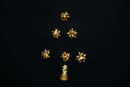 Creative idea Christmas or New Year tree made of golden bows on a black background.の写真素材