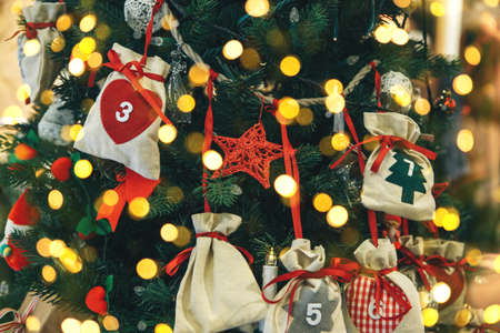 Various Christmas tree toys including star and gift bags on the Christmas tree. Festive background with many lights.の写真素材