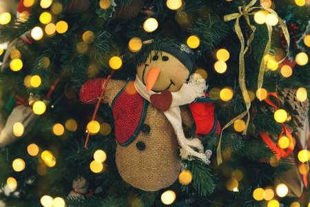 Close-up of a snowman Christmas tree toy. Festive background with many lights.の写真素材
