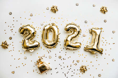 Golden inflatable holiday numbers 2021 on white background with golden confetti Christmas or New Year concept background.の写真素材