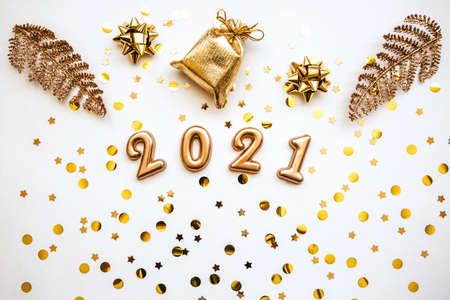 Gold holiday numbers 2021 on a white background with gold confetti and other items. Christmas or New...