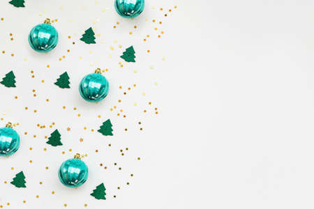 Mint colored Christmas balls and green little Christmas trees with golden confetti on a white background. There is empty space for text nearby.の写真素材