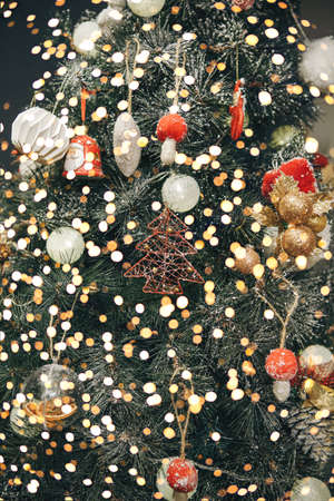 Christmas tree decoration festive background. Various toys and baubles and holiday lights on the tree.の写真素材