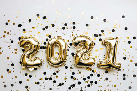 Golden inflatable holiday numbers 2021 on white background with golden confetti Christmas or New Year backgroundの写真素材