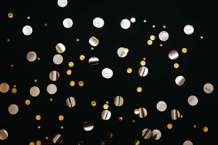 Gold and silver confetti on a black festive background.の写真素材