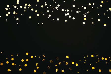 Gold and silver confetti on a black festive background. In the middle there is space for text or copy space.の写真素材