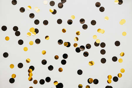 Scattered golden and silver confetti on a white abstract festive background.の写真素材