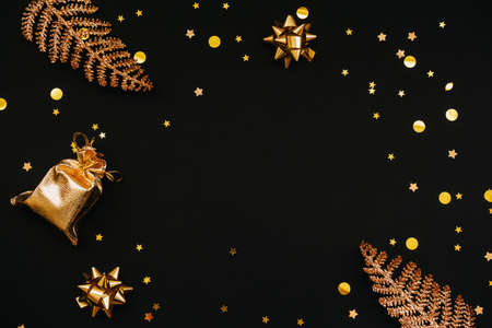 Various festive items and decorations in gold color on a dark or black background. In the middle there is space for text or copy space. Christmas or New Years concept.の写真素材