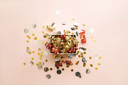 Open festive box with tinsel and confetti. Celebrating Christmas or New Years or winning a prize or a promotion or other holiday concept.の写真素材