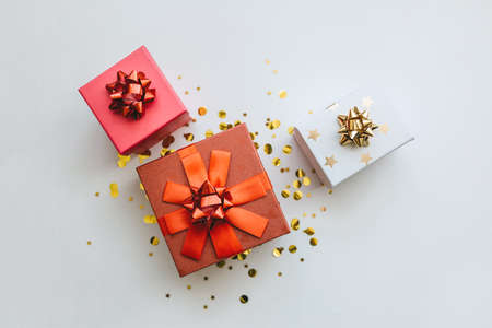 Lots of festive gift boxes on a white festive background with golden confetti.の写真素材