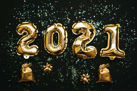 Gold numbers 2021 and next to them holiday items on a black or dark background. Christmas or New Year background.の写真素材