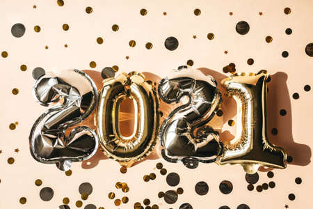 Silver and gold numbers 2021 on a pink background with confetti. Festive New Year and Christmas conceptual background.の写真素材