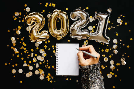 A girl writes goals for the 2021 New Year or a wish list or a letter to Santa in a notebook.の写真素材
