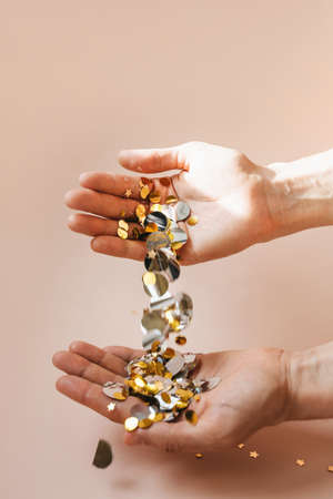 Human hands with falling confetti on a pink background. Festive concept.の写真素材