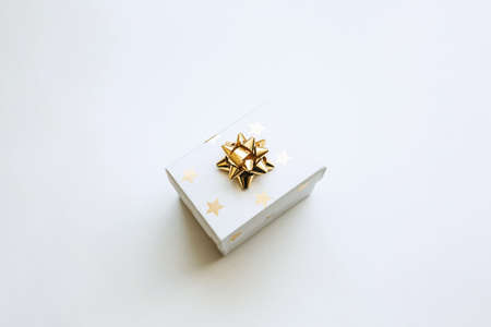 Gift box with a gold bow on a white background in a minimal style. Festive concept.の写真素材