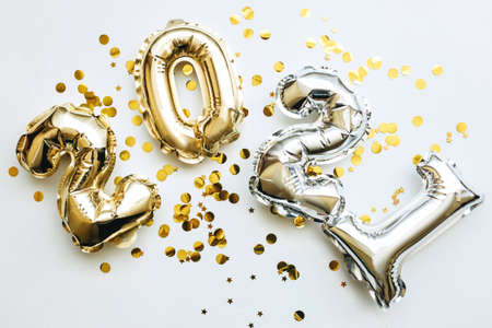 Gold and silver numbers 2021 and festive confetti on a white background. Conceptual New Year and Christmas background.の写真素材