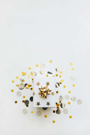 Gift box on a white background with golden confetti. Festive background. There is empty space for text at the top.の写真素材