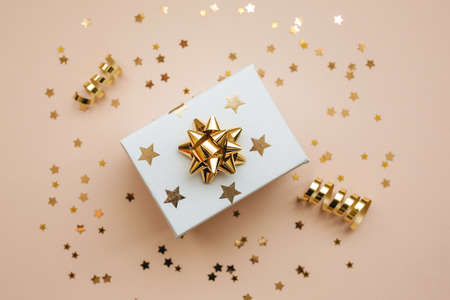 Gift box on a pink background with golden confetti. Festive background.の写真素材