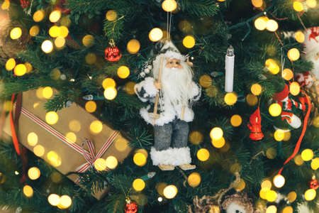 Close up of Santa Claus Christmas toy on the Christmas tree. There are lights around.