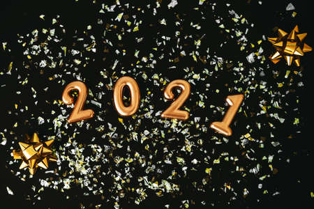 Gold numbers 2021 and glowing sparkles on a dark or black background. Christmas or New Year background.の写真素材