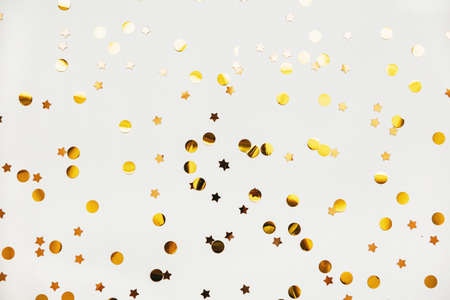 Scattered golden confetti on a white abstract festive background.の写真素材
