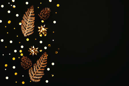 Gold bows, pine cones and confetti. Christmas or New Year dark background. There is empty space for text nearby.の写真素材