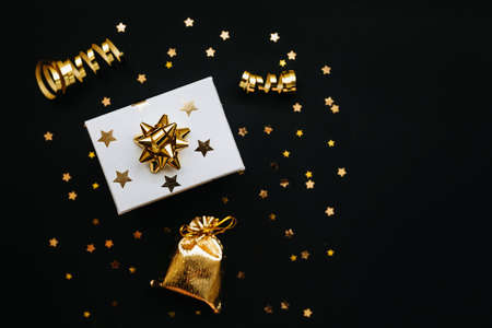 Gift box and various golden items on a black or dark background. Festive conceptual Christmas or New Year background or Black Friday saleの写真素材