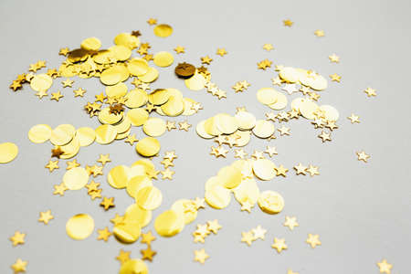 Scattered golden confetti on a white abstract festive background.の写真素材