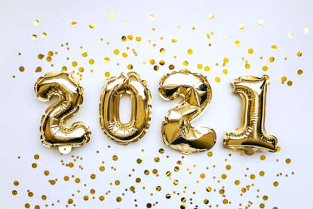 Golden inflatable holiday numbers 2021 on white background with golden confetti Christmas or New Year concept background.の写真素材
