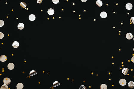 Gold and silver confetti on a black festive background. In the middle there is space for text or copy space.の写真素材