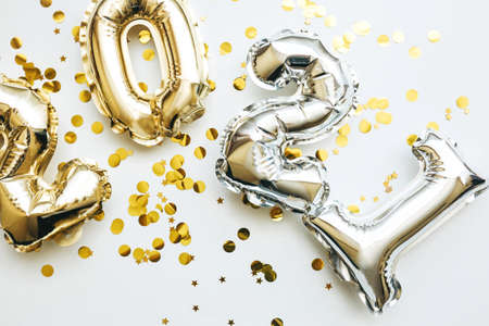 Gold and silver numbers 2021 and festive confetti on a white background. Conceptual New Year and Christmas background.の写真素材