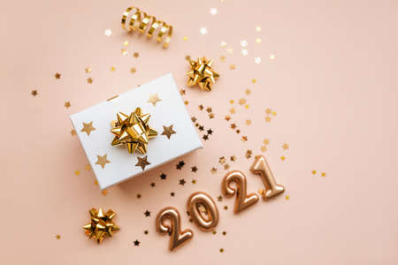 Top view of gift box and golden confetti and numbers 2021 on pink background. Festive New Year and Christmas background.の写真素材