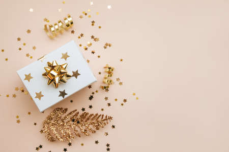 Gift box and various golden items on a pink background. Festive conceptual Christmas or New Year background. Nearby copy space.の写真素材