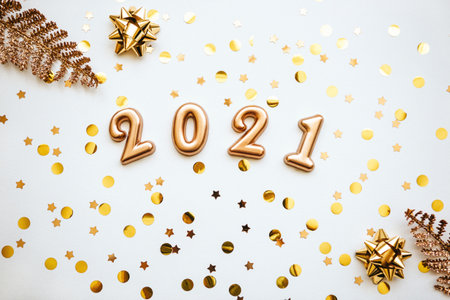Gold holiday numbers 2021 on a white background with gold confetti and other items. Christmas or New Year conceptual background.の写真素材