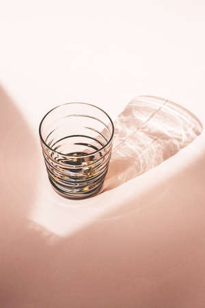 Glass on a pink background with long shadow from sunlight in a minimal style.の写真素材