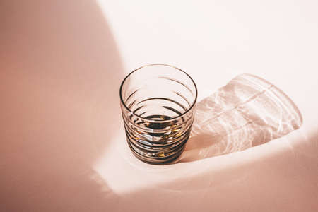Glass on a pink background with long shadow from sunlight in a minimal style.の写真素材