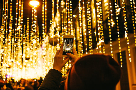 The girl takes pictures of Christmas or New Year's lights on the phone.の写真素材