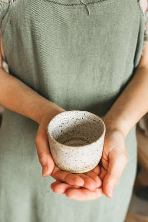 An artisan woman holds a handmade ceramic cup in her hands. Small business