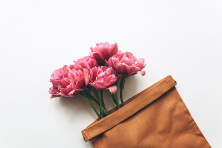 Pink tulips in a canvas bag on a white background. Beautiful festive background. Copy space, flat layの写真素材