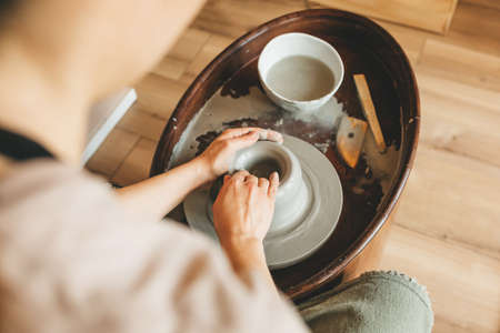 Top view of female pottery maker works in clay studio on pottery wheel. Handmade, design and workshop concept.の写真素材