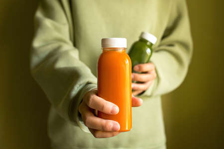 The girl is holding bottles of freshly squeezed juice in her hands. The concept of a healthy lifestyle, diet or detoxの写真素材