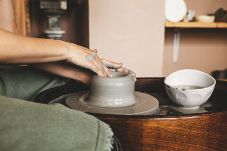 A female craftsman works in a clay workshop on a potters wheel. The concept of creative people.の写真素材