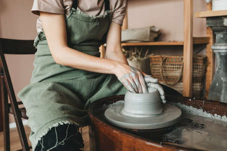 A female craftsman works in a clay workshop on a potters wheel. The concept of creative people.の写真素材