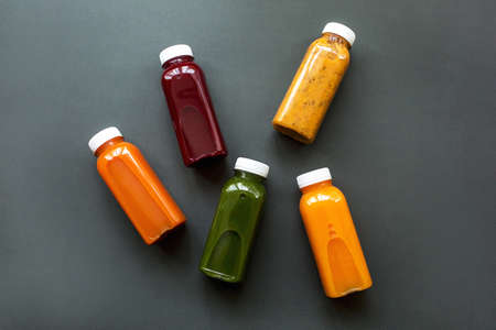 Fresh juices or cocktails of fruits and vegetables in bottles on a gray background. The concept of a healthy diet or dietの写真素材
