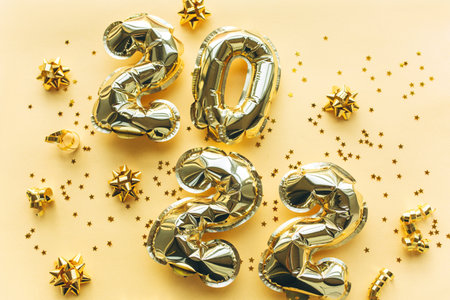 Balloons made of gold foil with the numbers 2022 on a gold background with gold sequins. Celebrating Christmas, New Years and holiday concept. Flat lay, top view.の写真素材
