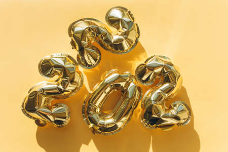 Balloons made of gold foil with the numbers 2022 on a gold background. Celebrating Christmas, New Years and holiday concept. Flat lay, top view.の写真素材